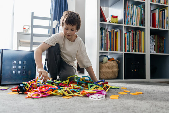 Boy playing with colorful magnetic construction tiles on floor