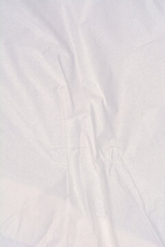 Detailed macro view of a thin white packaging paper surface showing soft creases and vertical folds.