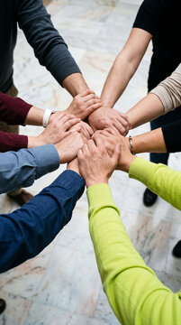 Pile of diverse hands clasped together, symbolizing unity, teamwork, and support, representing collaboration and community strength.