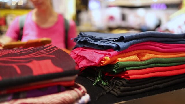 Close-up of neatly folded colorful lightweight scarves or shawls stacked on display shelves in a clothing store, boutique or department store. Retail shopping, fashion accessories and apparel.