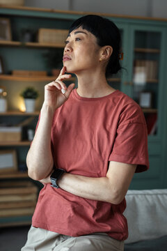 Asian woman contemplating, thinking about future at home