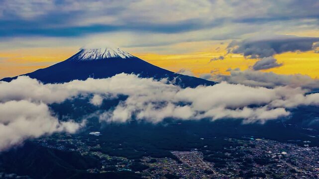 A breathtaking cinematic sunset time-lapse capturing the majestic snow-capped summit of Mount Fuji bathed in warm alpenglow as dusk settles over a rolling ocean of clouds.