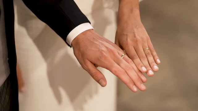 Bride And Groom Hands Side By Side Showing Matching Gold Wedding Bands After The Ceremony