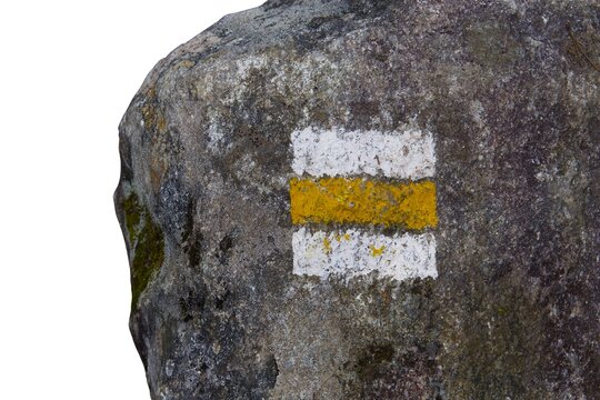 Rock with a yellow and white painted hiking trail marker isolated on a white background