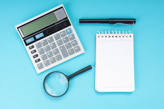 Flat Lay of Magnifying Glass Under Calculator with Pen and Notebook for Financial Audit
