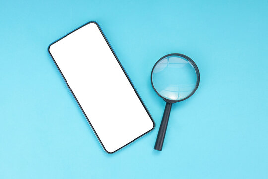 Flat Lay of Smartphone with Magnifying Glass on Blue Surface