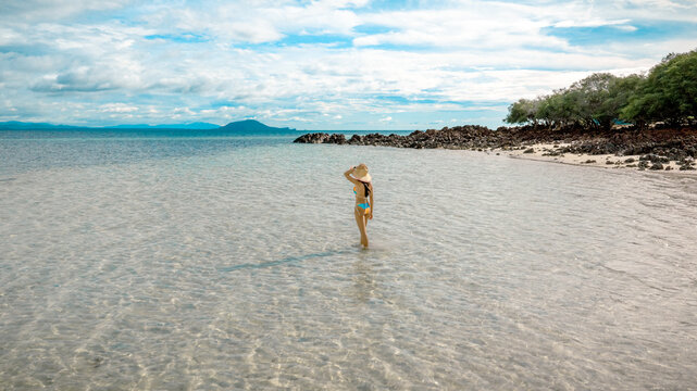 Woman tourist stay happy moment at the edge of the sea beach under shallow of the crystal clear water in summer trip on tropical island island