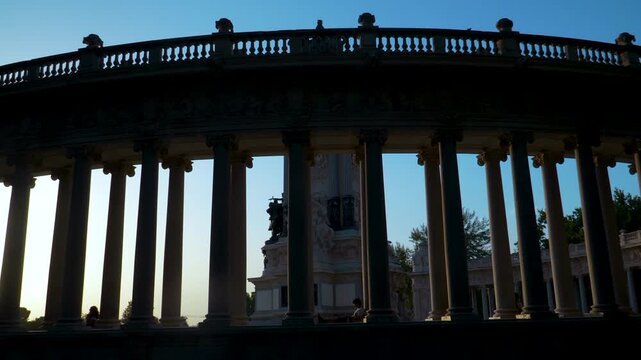 A low angle silhouette of the iconic semicircular colonnade at Buen Retiro Park during golden hour. Captures historic Spanish architecture and European travel vibes.