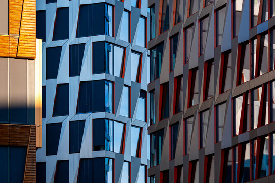 Colorful modern facade with geometric windows and deep shadows forming a repeating architectural pattern across a dense contemporary urban building exterior