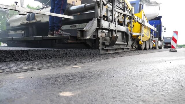 Slowly driving roller laying new asphalt layer. Special machinery making road in countryside area. Compactor constructing highway. Heavy machinery repairing road. Roadwork process. Roadway repair