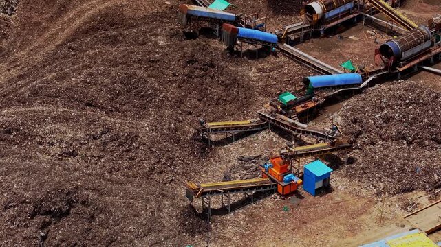 Aerial drone shot showing garbage dump yard with waste piles and conveyor machinery for waste sorting and processing operations at this site in Chennai, Tamil Nadu, India