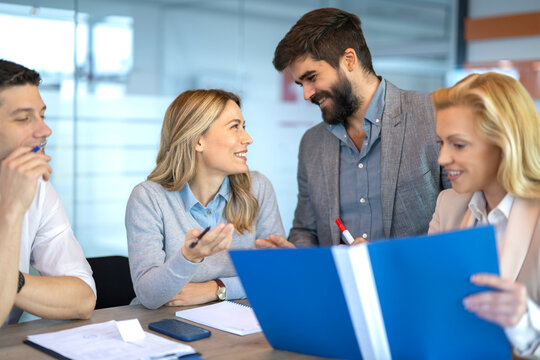 Business colleagues discussing ideas and reviewing documents during a collaborative office meeting with folders and notes.