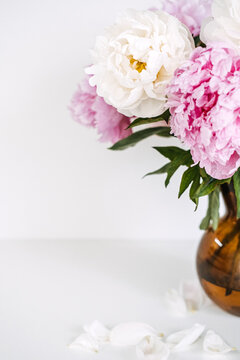 Fresh bouquet of pink and white peonies stands in vase on white surface with copy space. Premium boutique flower delivery, online florist shop banner, seasonal bouquet subscription service.