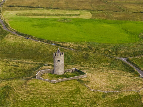 Aerial view of Doonagore Castle, a historic stone tower house surrounded by lush green fields and stone walls in the rural landscape of Doolin, County Clare, Ireland.