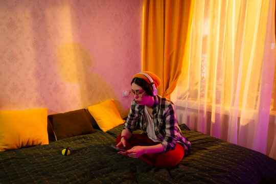 Girl interacting online alone in room. Concept of digital companionship. Wide shot