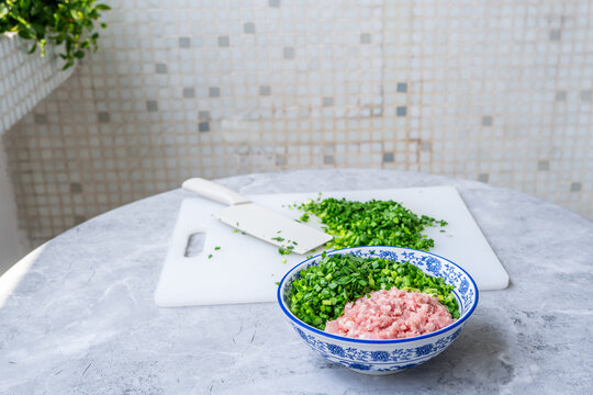 Dumpling filling ingredients&mdash;chopped chives and ground pork.
