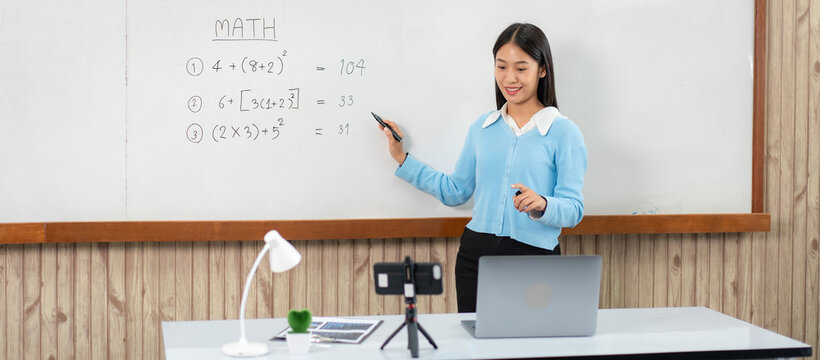 Female tutor standing in front of whiteboard and writing math eq
