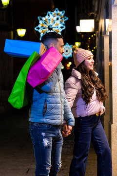 Couple christmas shopping, holding hands, enjoying city street during holiday season night