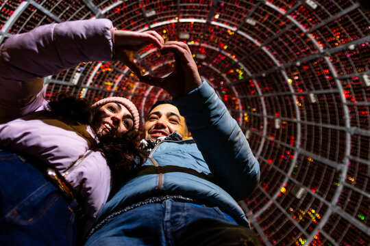Young couple expressing love and joy against a backdrop of festive holiday lights