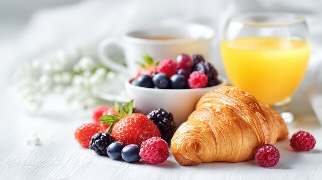 Fresh breakfast with croissant berries tea and juice on table in soft light creating healthy morning meal