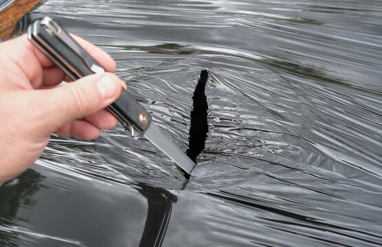An incision made in the upper part of an IBC container, wrapped in black UV-resistant plastic, to create an opening in the container.
