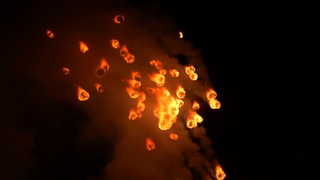 Fiery debris suspended in dense smoke against a black background with glowing fragments