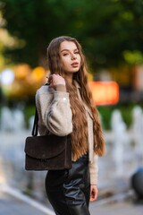 confident woman walking on urban street with handbag and jacket in side view, showcasing fashion and style in brown and beige tones, modern and dynamic mood, for editorial. © flywish