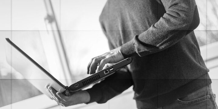 Senior businessman standing and working on his laptop, geometric pattern