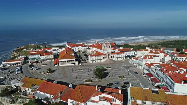 Aerial view of the Santuario de Nossa Senhora da Nazare surrounded by red-tiled rooftops and the Atlantic Ocean in Nazare, Leiria District, Portugal.