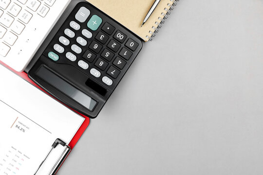 Top view of black calculator, white keyboard, financial report, and notebook on gray background with copy space. Concept of digital accounting, financial analysis, and business budget planning.