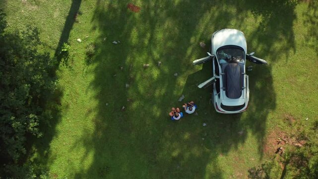 Parked SUV and travelers fill overhead aerial view in a forest clearing near Mazeri, Svaneti, supporting car camping, outdoor recreation, road trips and remote Georgian mountain tourism media.