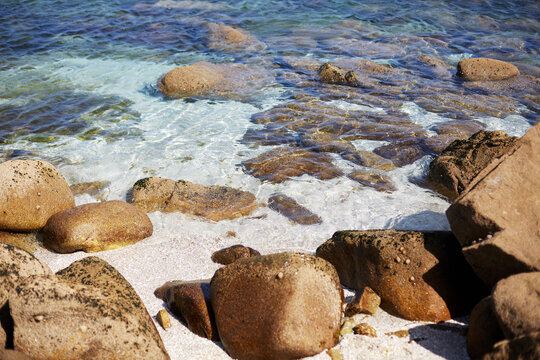 Granite boulders and crystal clear shallow sea water on sandy shore in Cies Islands Galicia Spain