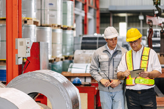 Factory Technicians Engineer Workers Team Young with Senior Supervisor Inspecting Steel Roll Coils Stock Inventory in Metal Heavy Industry Plant.