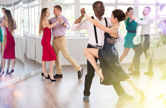 Dance training in group - men and women of different nationalities and different ages dance tango or bachata in a dance studio