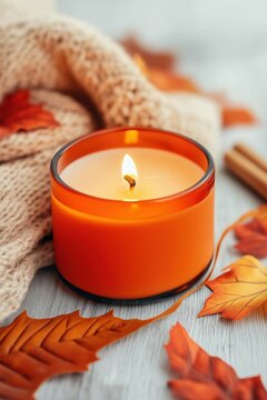 Hand-poured candle in orange color on wooden surface with autumn