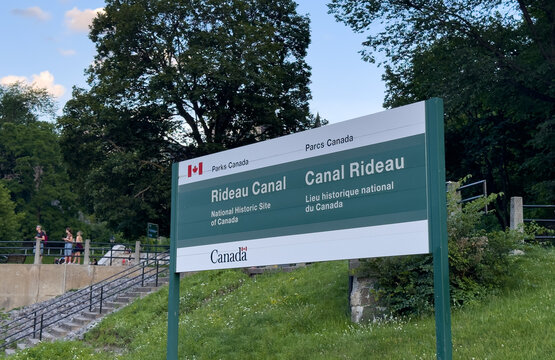 Ottawa, Ontario, Canada. August 25, 2026. Low angle shot of the official Parks Canada Rideau Canal sign on a grassy hill outdoors.
