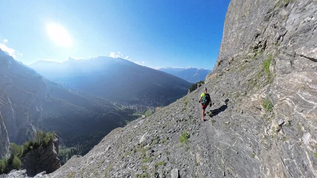 Hiker traversing steep rocky ledge on Dauberhorn via ferrata near Leukerbad Switzerland