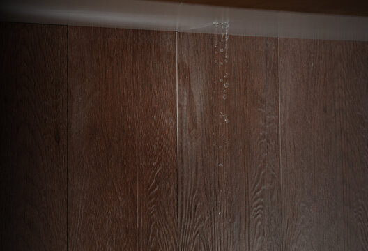 Heavy storm rain create water flow from edge of ceiling and dirty stain on wall. Water leaking from top ceiling as droplets and flow in old house