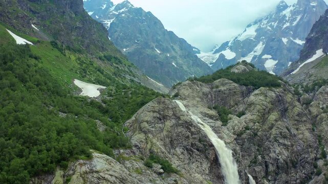 Shdugra Waterfall and Ushba glaciers fill ascending aerial view above a rugged alpine gorge near Mazeri, Svaneti, supporting mountaineering tourism, glacial geography and Georgian travel promotion.