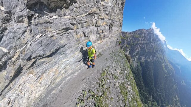 Climbers traversing steep rocky ledge on Dauberhorn via ferrata near Leukerbad Switzerland