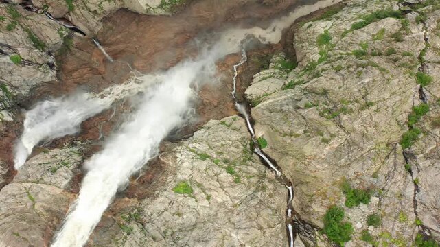 Shdugra Waterfall surges in aerial view through split rocky channels below Ushba glaciers near Mazeri, Svaneti, supporting hydrology studies, geotourism, erosion analysis and Georgian adventure travel