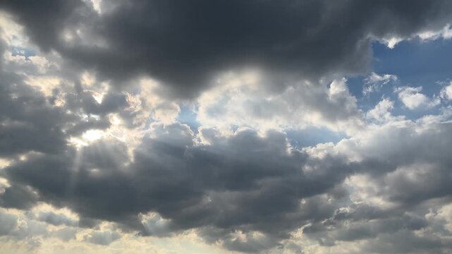 Dramatic dark storm clouds with sun rays piercing through the sky during a cloudy day weather phenomenon