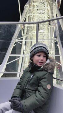 Smiling boy riding Ferris wheel at illuminated Christmas fair