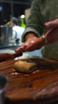 Woman's hands preparing and rolling dough for paratha on a wooden board in a domestic kitchen