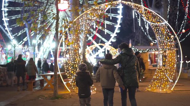 Mother and children enjoying festive lights at Christmas fair