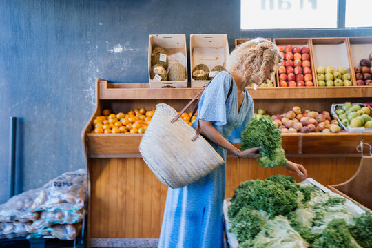 Focused Middle Aged Woman Choosing Fresh Leafy Greens at Local Fruit and Vegetable Market