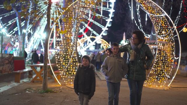 Family walking through illuminated Christmas market at night