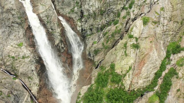 Shdugra Waterfall cascades in aerial view around fractured cliffs below Mount Ushba near Mazeri, Svaneti, supporting geotourism, rock erosion studies, trekking promotion and Georgian nature media.
