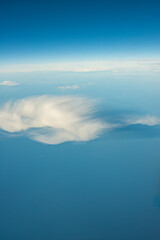 Fototapeta premium Wispy Feathered Cloud Drifting Alone Over a Calm Sea and Pale Blue Sky