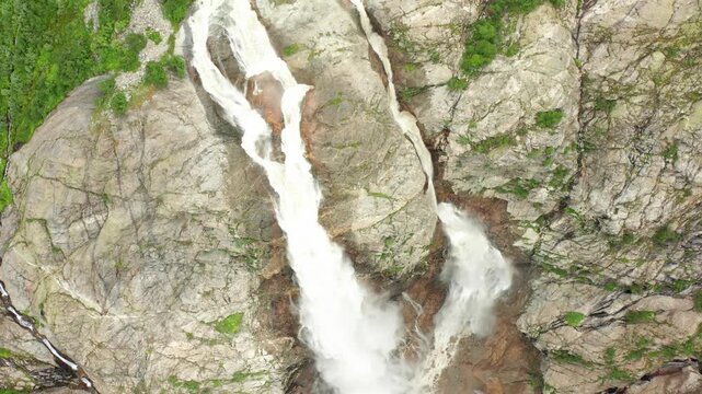 Shdugra Waterfall cascades in aerial view beside weathered cliff walls below Mount Ushba near Mazeri, Svaneti, supporting geology tourism, meltwater research, conservation media and trekking promotion